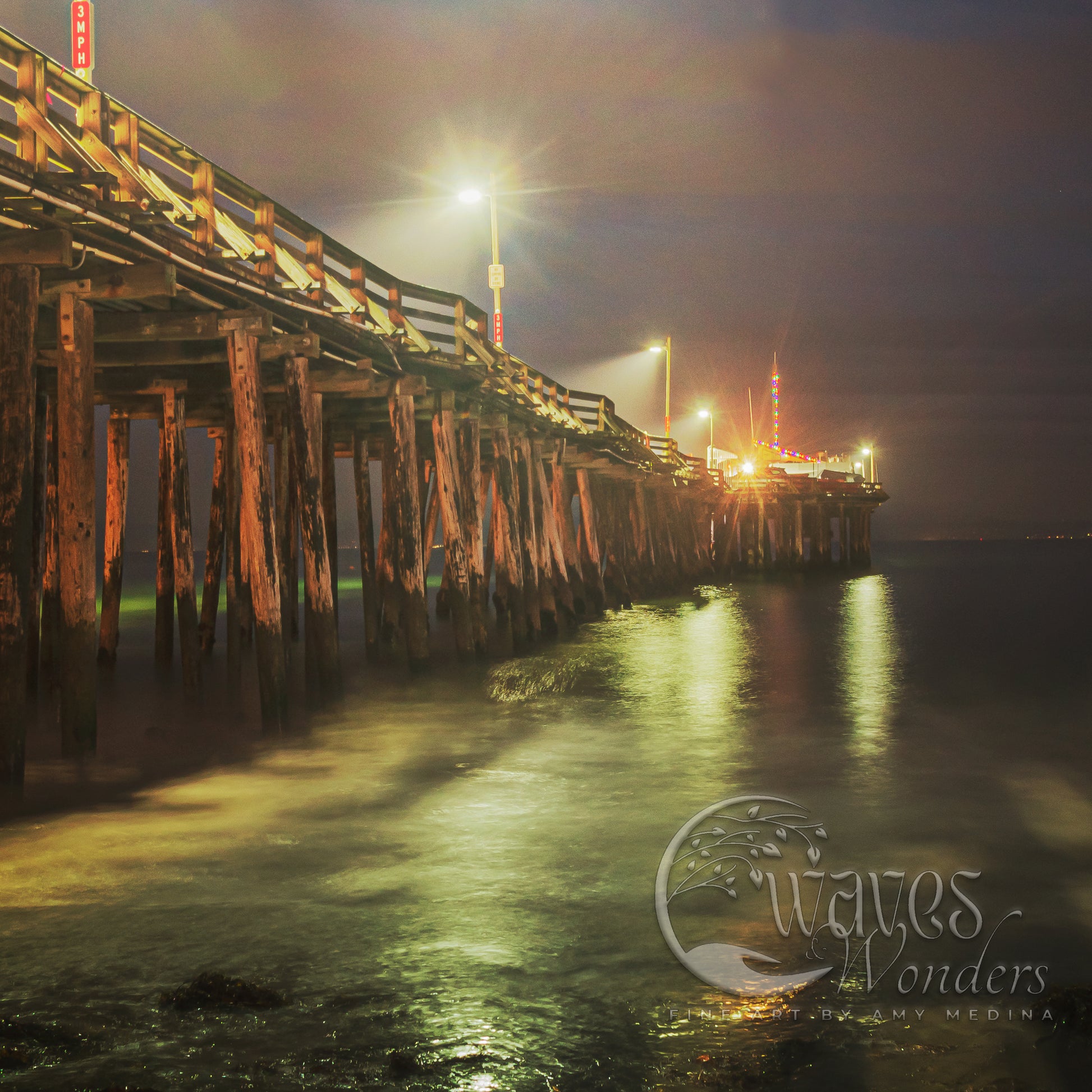 a pier at night with lights reflecting off the water