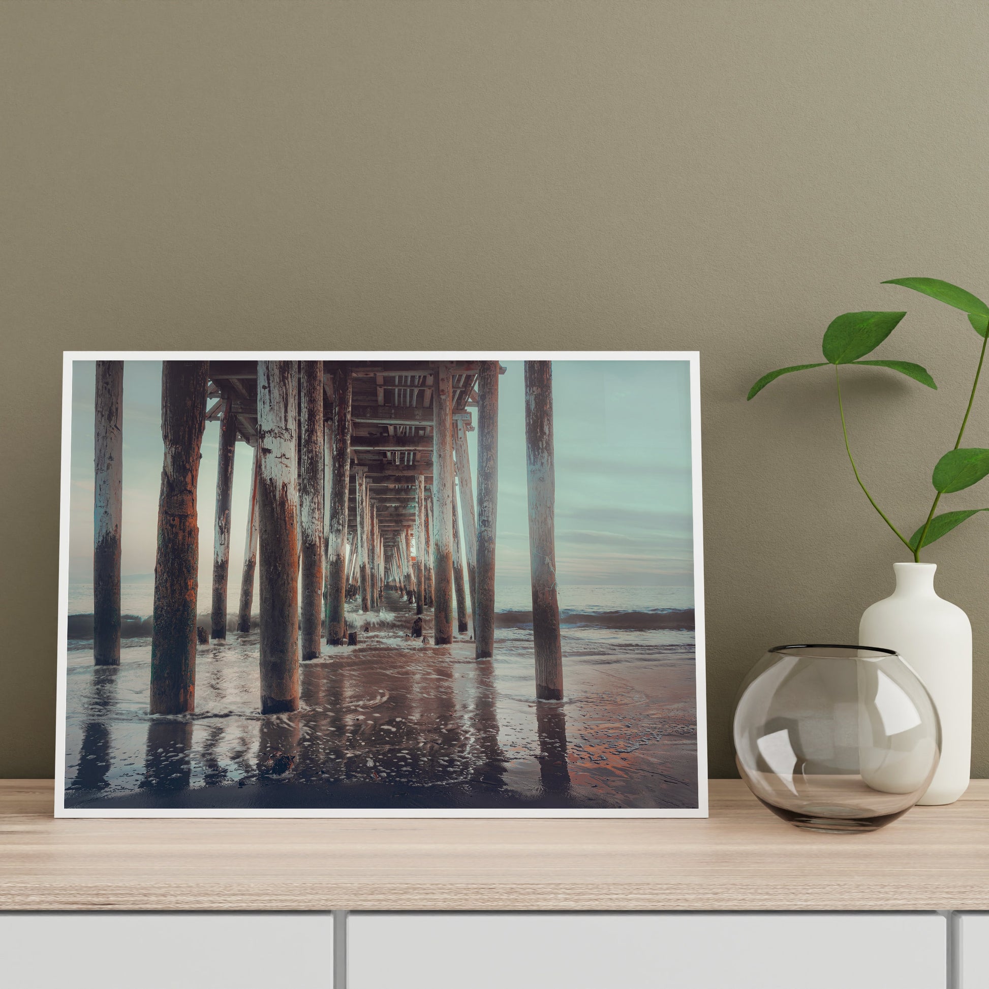 a picture of a pier on a table next to a vase with a plant