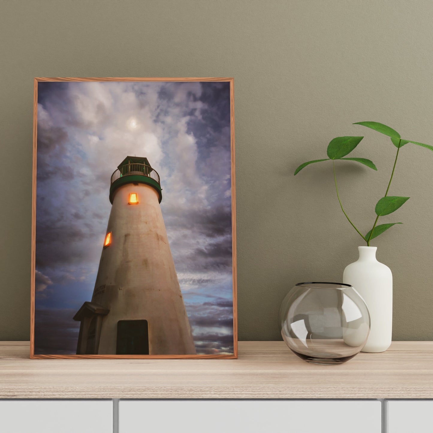 a picture of a lighthouse on a shelf next to a vase